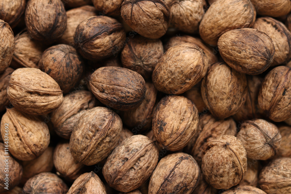 Heap of walnuts in shell, close-up, top view. Healthy eating. Harvest, agriculture. Walnuts, selective focus, background Heap of walnuts in shell, close-up, top view. Healthy eating. Harvest, agriculture. Walnuts, selective focus, background