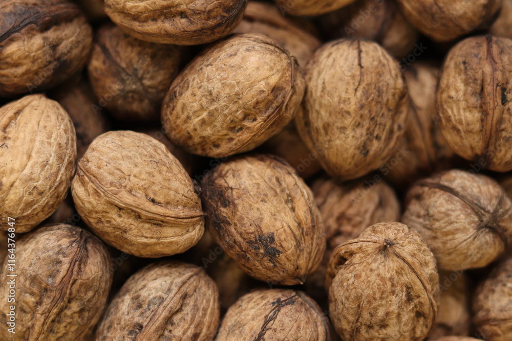 Heap of walnuts in shell, close-up, top view. Healthy eating. Harvest, agriculture. Walnuts, selective focus, background Heap of walnuts in shell, close-up, top view. Healthy eating. Harvest, agriculture. Walnuts, selective focus, background