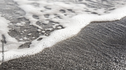 Black and white coastal scene capturing gentle waves meeting fine sand texture on a serene shoreline.