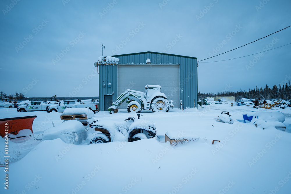 Cars, Tractor, and Machinery in Front of a Garage Covered in Snow During Winter in Anticosti Island, Quebec