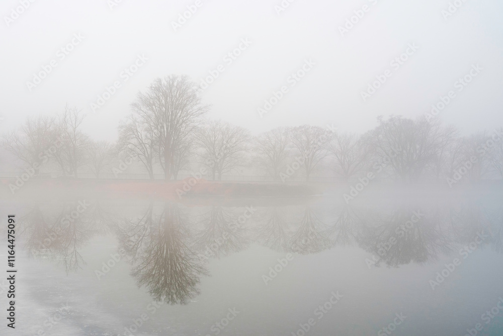 Foggy winter landscape with trees in the mist and snow-covered ice over the lake in New Haven, Connecticut, USA Foggy winter landscape with trees in the mist and snow-covered ice over the lake in New Haven, Connecticut, USA