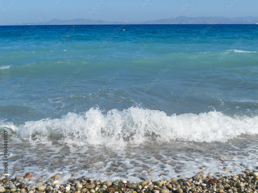 Waves crashing on a pebbled beach by the sea Waves crashing on a pebbled beach by the sea