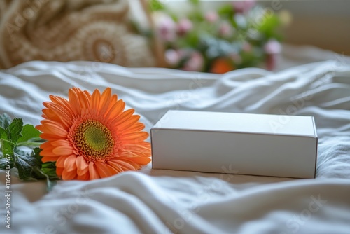 Delivered gift box resting on soft fabric with colorful flowers nearby in a b...