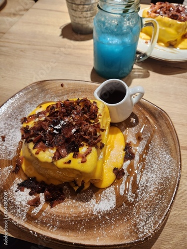 brunch consisting of a refreshing beverage, French toast with bacon and cheeddar cheese.