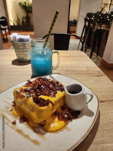 brunch consisting of a refreshing beverage, French toast with bacon and cheeddar cheese.
