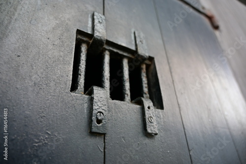 An old, black cell door in a prison which is called 