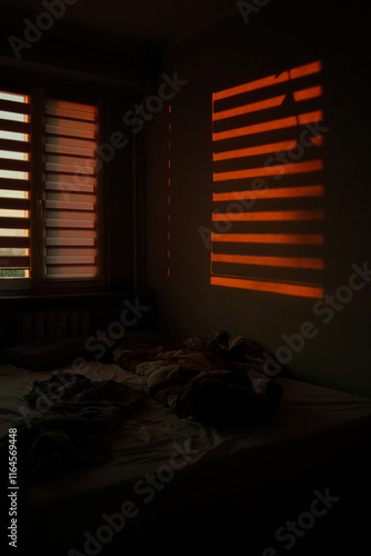 the red light of the sunset shining into the room through the blinds
