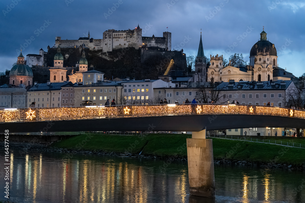 Fototapeta premium Makartsteg (love lock padlock bridge) over the Salzach River, with the fortress in background. Salzburg cityscape at night