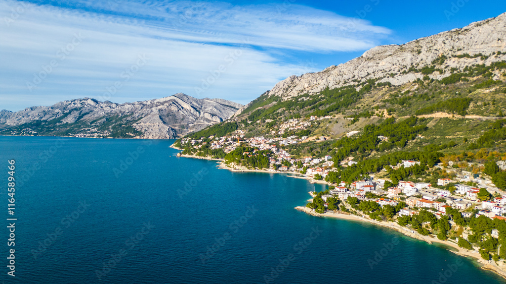Obraz premium A stunning aerial view of Brela, Croatia, showcasing the iconic Kamen Brela rock formation surrounded by crystal-clear turquoise waters. The coastline is dotted with pristine beaches