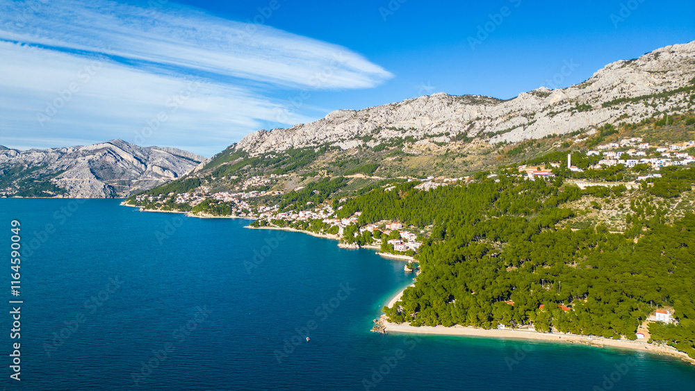 A stunning aerial view of Brela, Croatia, showcasing the iconic Kamen Brela rock formation surrounded by crystal-clear turquoise waters. The coastline is dotted with pristine beaches A stunning aerial view of Brela, Croatia, showcasing the iconic Kamen Brela rock formation surrounded by crystal-clear turquoise waters. The coastline is dotted with pristine beaches