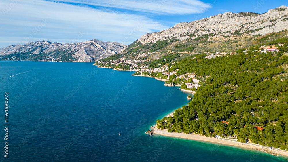 Obraz premium A stunning aerial view of Brela, Croatia, showcasing the iconic Kamen Brela rock formation surrounded by crystal-clear turquoise waters. The coastline is dotted with pristine beaches