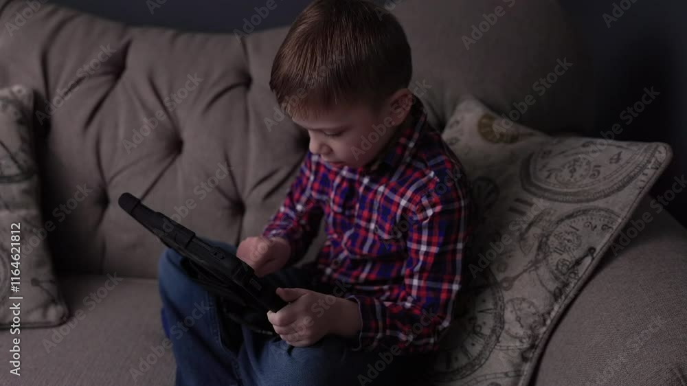 Portrait of Cute Boy Playing Game on Tablet. Relaxing in Living Room. Portrait of Cute Boy Playing Game on Tablet. Relaxing in Living Room.