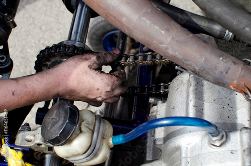 Hands of a boy racer who adjusts the chain on his sports car. photo