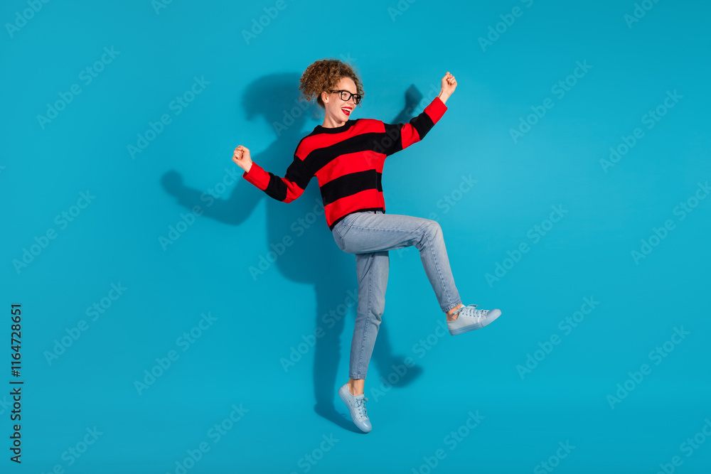 Young woman in a striped sweater posing against a light blue background, portraying joy and fashion. Young woman in a striped sweater posing against a light blue background, portraying joy and fashion.