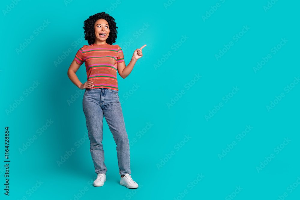 Full size photo of pretty young girl indicate finger empty space isolated on teal color background Full size photo of pretty young girl indicate finger empty space isolated on teal color background