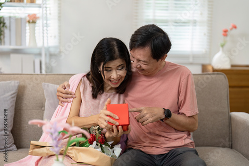 Happy Couple Celebrating Valentine's Day with Gift Exchange and Flowers in Cozy Living Room Setting photo