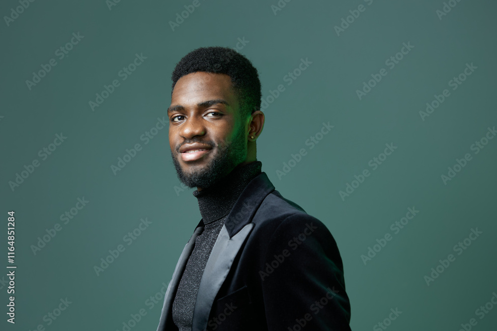 Fototapeta premium Confident african american man in stylish black outfit posing against vibrant green background