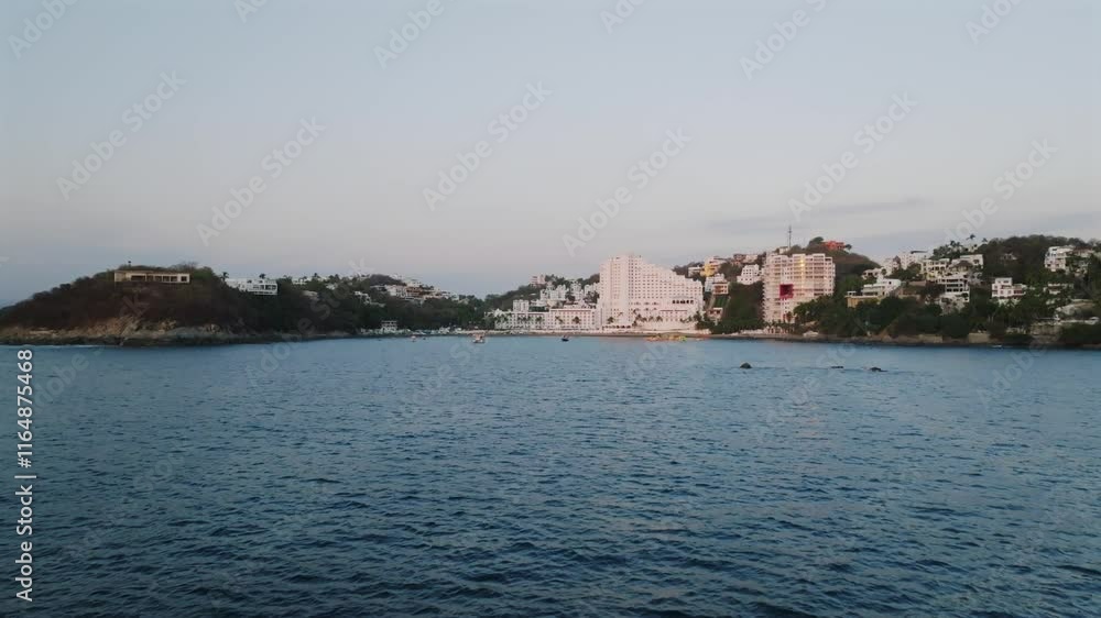 Dolly in flyover blue waters of the Pacific at La Audiencia Beach, Manzanillo, Colima reveals anchored boats and luxury resort Dolly in flyover blue waters of the Pacific at La Audiencia Beach, Manzanillo, Colima reveals anchored boats and luxury resort