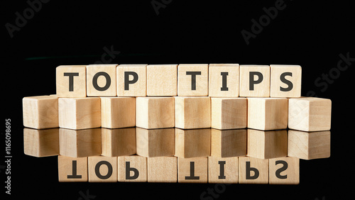 Wooden blocks arranged to spell out top tips showcase essential business and finance advice. The reflective surface emphasizes the importance of clear communication in professional settings photo