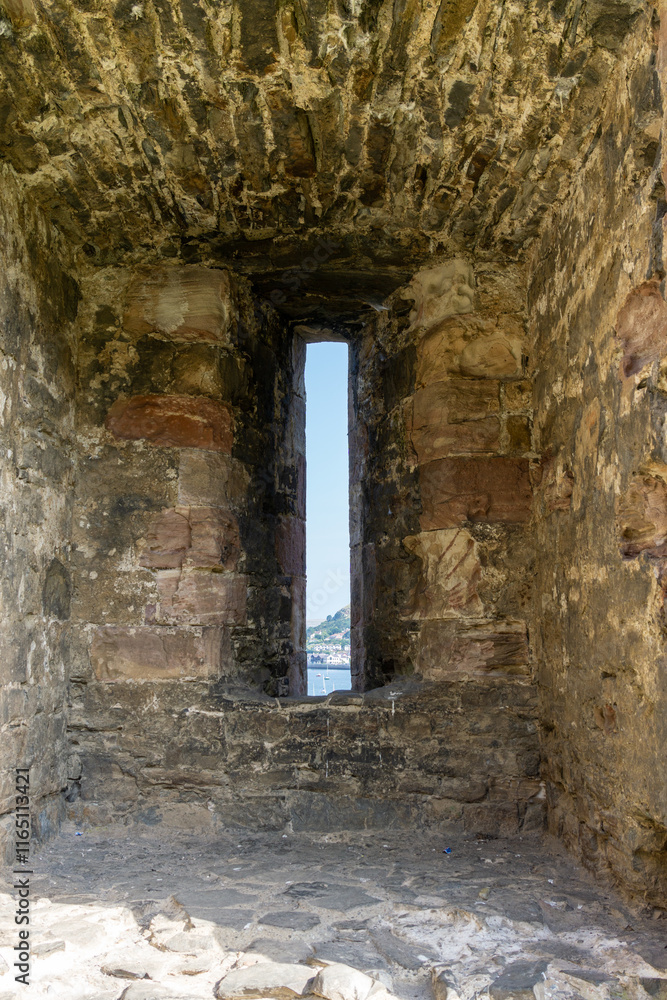 Narrow view through medieval arrow-slot in castle wall Conwy Wales Narrow view through medieval arrow-slot in castle wall Conwy Wales