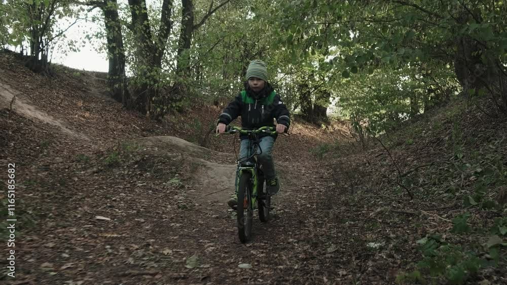 Little teenage boy on MTB mountain bike riding downhill in park. Extreme cycling for kids. Concept travel holidays children lifestyle sport activities. Male kid child cycling in forest. Cinematic shot Little teenage boy on MTB mountain bike riding downhill in park. Extreme cycling for kids. Concept travel holidays children lifestyle sport activities. Male kid child cycling in forest. Cinematic shot