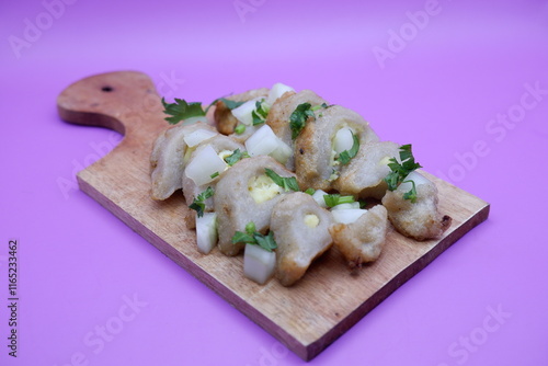 empek-empek on wooden cutting board. empek-empek isolated on purple background. empek-empek is a typical food from Palembang, South Sumatra, Indonesia photo