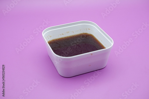 empek-empek sauce in a white square container. empek-empek sauce isolated on purple background. sauce that is usually served with empek-empek, a typical food from Palembang, Indonesia photo