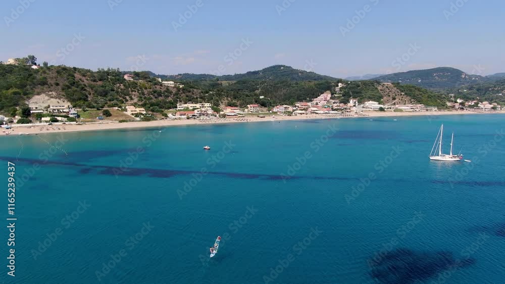 Aerial view of turquoise ocean with sailboats and windsurfers near a sandy beach Aerial view of turquoise ocean with sailboats and windsurfers near a sandy beach