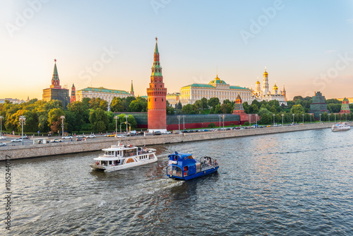 View of Kremlin with Vodovzvodnaya tower, Grand Kremlin Palace from repaired Bolshoy Kamenny Bridge in Moscow city on sunny summer day. Cruise ship sails on the Moscow river