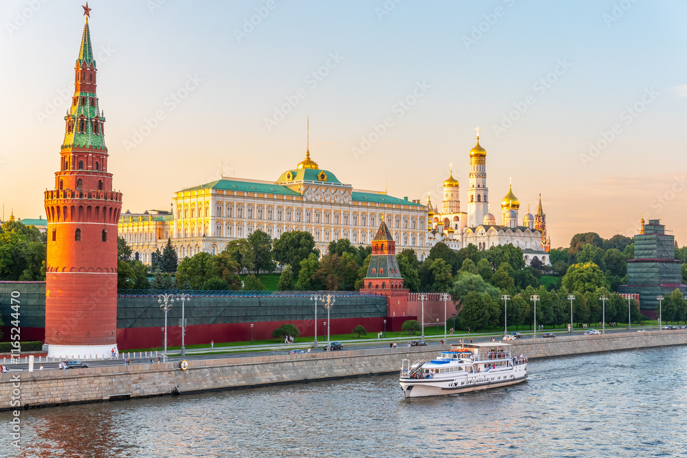 Obraz premium View of Kremlin with Vodovzvodnaya tower, Grand Kremlin Palace from repaired Bolshoy Kamenny Bridge in Moscow city on sunny summer day. Cruise ship sails on the Moscow river