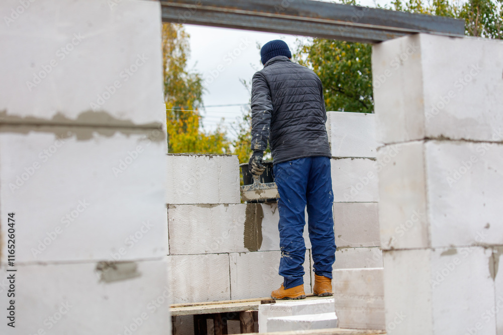 Fototapeta premium A man in a blue jacket and blue pants is working on a wall