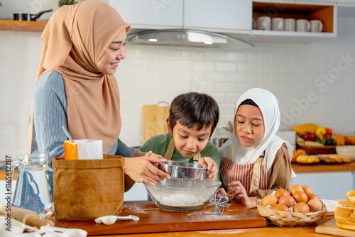 Little boy and girl of muslim family help and learn from their mother to cook relate to cooking flour and ingredients in the kitchen with happiness. photo