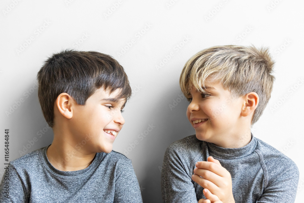 Cheerful children brothers looking at each other and smiling against a white background. Cheerful children brothers looking at each other and smiling against a white background.
