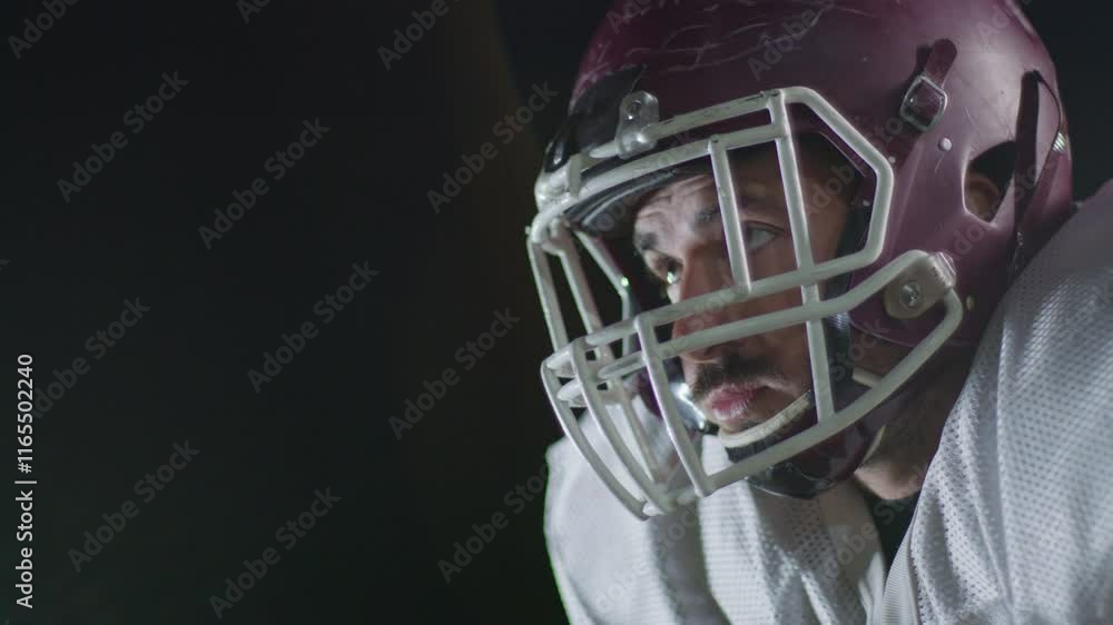 Portrait of determined professional American football player in helmet in dramatic light throwing up ball ready for game. Team game and extreme sport spirit business leadership concept Portrait of determined professional American football player in helmet in dramatic light throwing up ball ready for game. Team game and extreme sport spirit business leadership concept