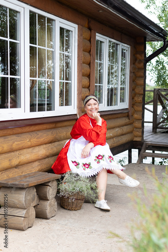 a woman in a national Udmurt costume. small nations. A village woman sits at a wooden house photo