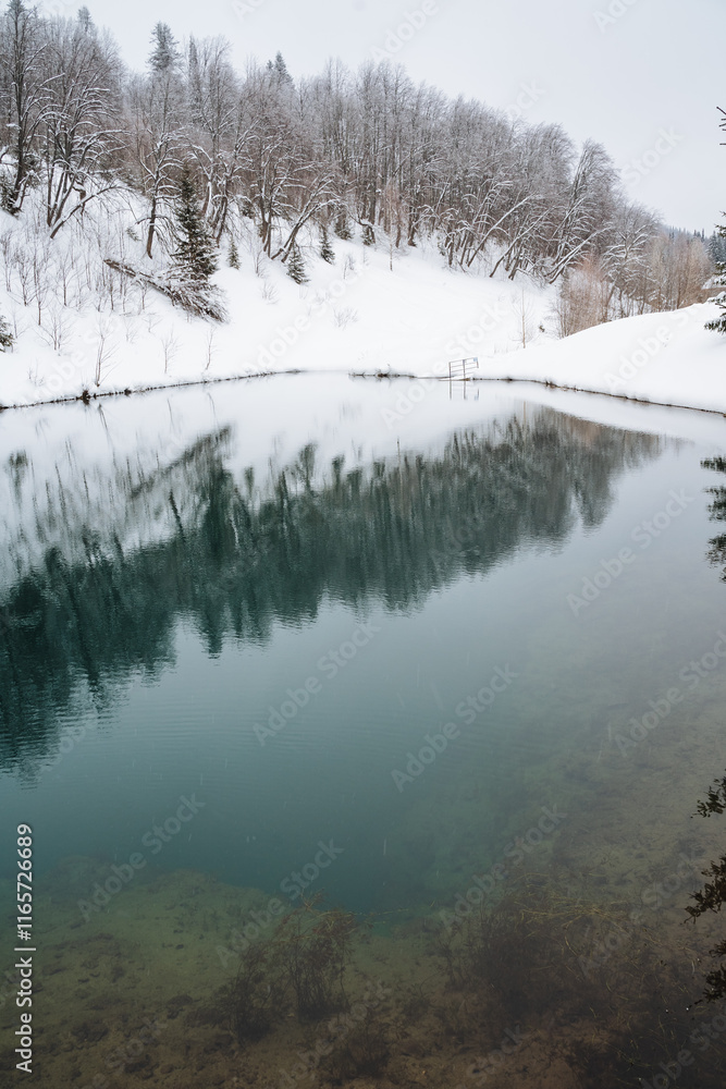 Amidst a picturesque, snowy forest, there lies a serene lake perfectly nestled, where the trees surrounding it are beautifully reflected in the calm, icy waters surface Amidst a picturesque, snowy forest, there lies a serene lake perfectly nestled, where the trees surrounding it are beautifully reflected in the calm, icy waters surface