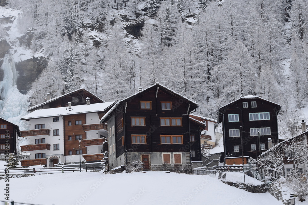 Naklejka premium Snowy cabins in the mountains; Snow-covered chalets in Swiss Alps; Switzerland at wintertime in the mountains