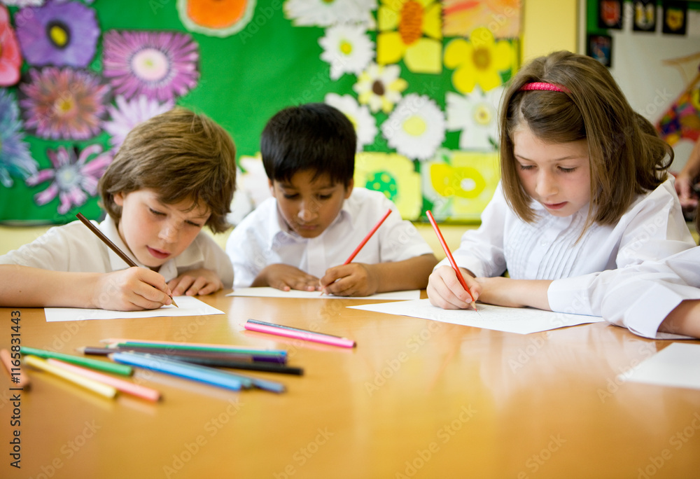 Elementary School: Artists. A small group of young primary school children in the classroom developing their creative drawing and art skills. Elementary School: Artists. A small group of young primary school children in the classroom developing their creative drawing and art skills.