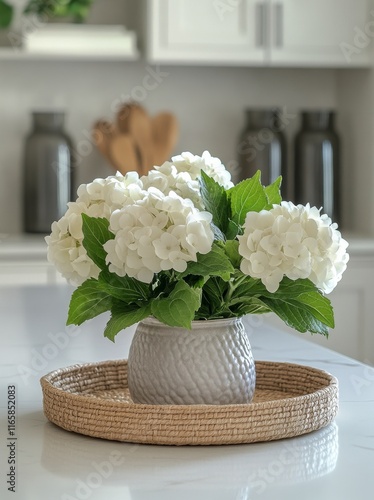 Elegant white hydrangeas in a textured vase on a kitchen countertop with natu...