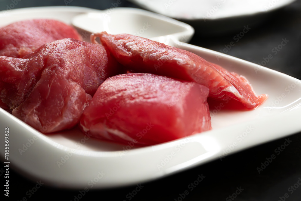Sliced raw tuna fish on white rectangular plate on black table, fish steaks close-up Sliced raw tuna fish on white rectangular plate on black table, fish steaks close-up