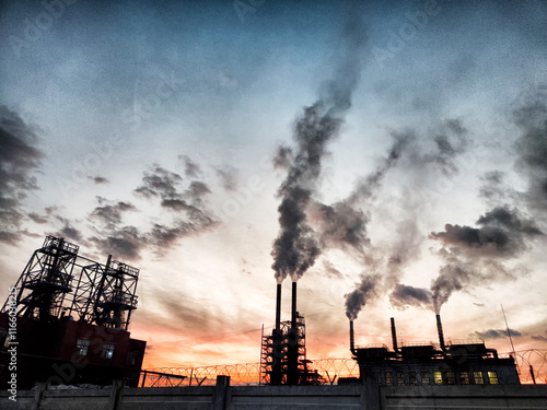 Dirty smoke billows from industrial pipes at sunset, highlighting environmental pollution in the skyline photo