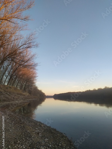 Beautiful landscape on the river bank with reflection of trees and sky