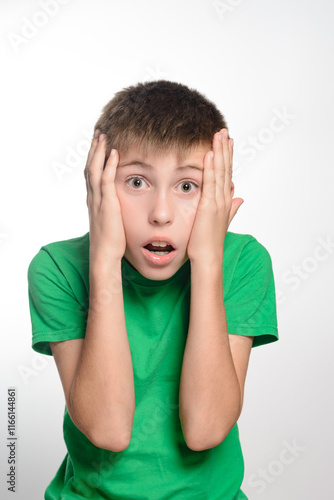 Foto A young boy wearing a green shirt looks shocked