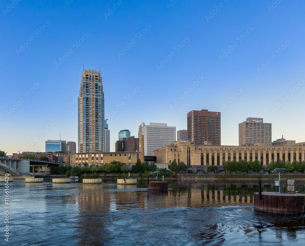 Obraz premium Minneapolis skyline reflected in the Mississippi River at dawn. City buildings and a bridge are visible. Mississippi River, Minneapolis, Minnesota, United States