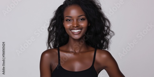 A woman with a big smile on her face. She is wearing a black tank top. Concept of happiness and confidence