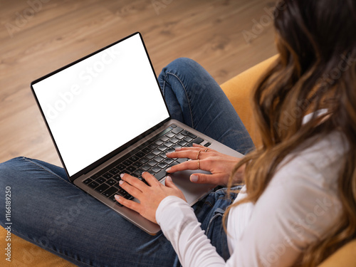 Over shoulder laptop mock up, young caucasian brunette teen girl student sitting couch at home relaxing using holding laptop with empty blank screen. Online learning, watching movie, shopping online.