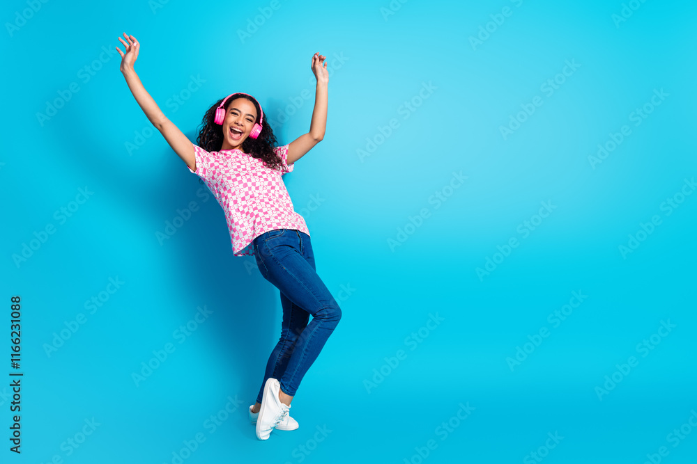 Obraz premium Full length photo of cheerful pretty lady dressed pink t-shirt earphones dancing empty space isolated blue color background