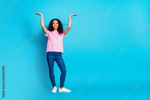 Full length photo of adorable lovely girl wear print t-shirt showing arms up empty space isolated blue color background photo