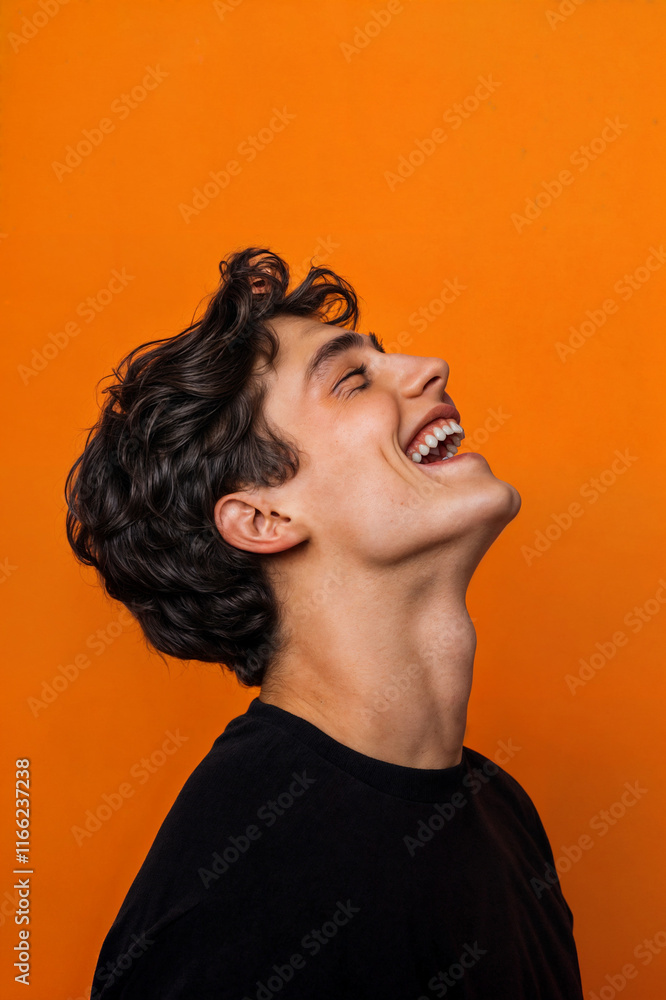 The image shows a person with curly hair and a black shirt, laughing with their head tilted back against an orange background
