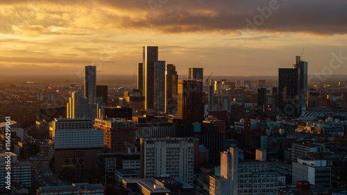 The golden hour highlights the stunning cityscape of Manchester, as the low sun creates a beautiful interplay of light and shadows on the buildings.